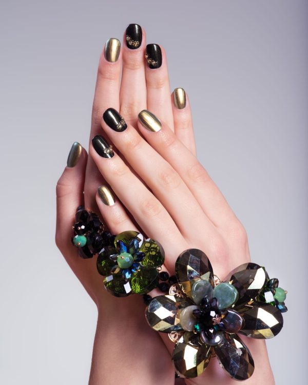 Beautiful woman's nails with creative manicure and jewelry. Studio image