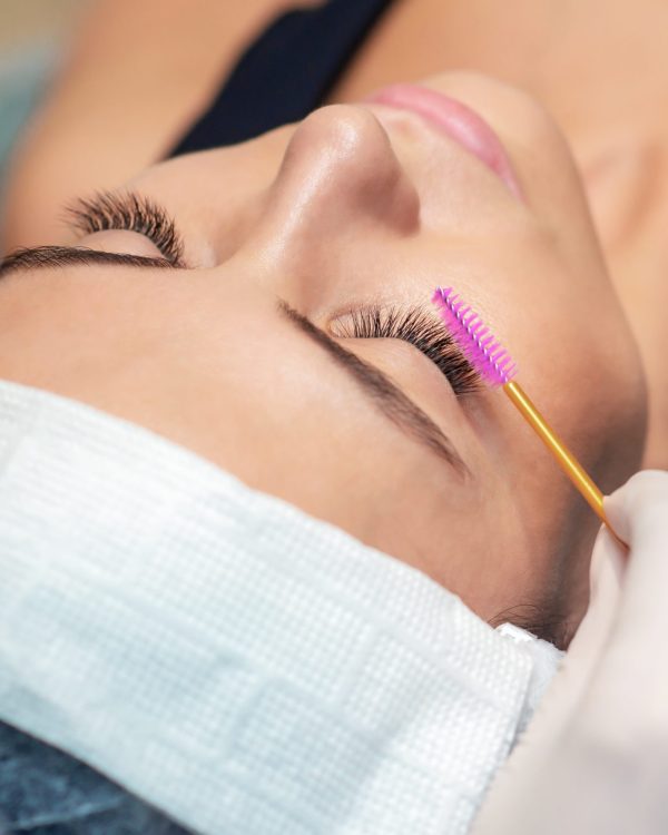 Young woman receiving eyelash extension in a beauty salon, Eyelash extension procedure.